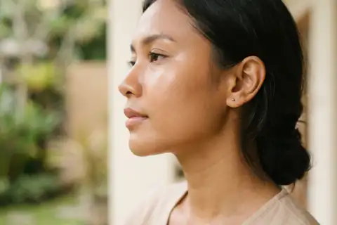 Close-up pipi halus bercahaya dengan pori-pori tenang dan rona kulit merata
